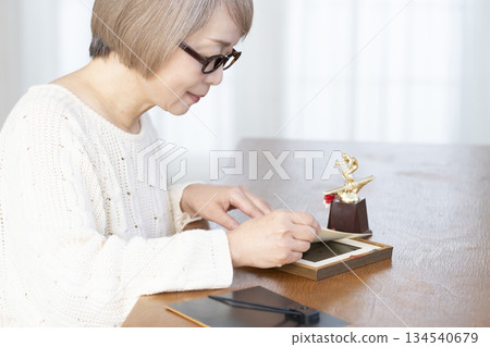一位老婦人在客廳裝裱照片 一位老婦人在客廳裝裱照片 134540679