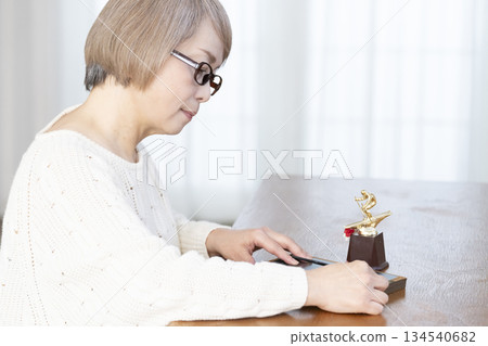 Senior woman framing photos in the living room 134540682