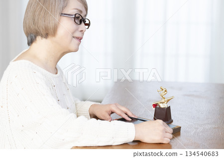 Senior woman framing photos in the living room Senior woman framing photos in the living room 134540683