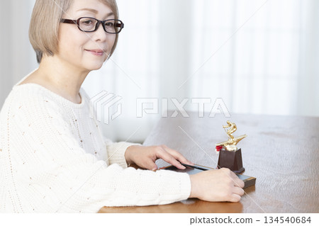 一位老婦人在客廳裝裱照片 一位老婦人在客廳裝裱照片 134540684