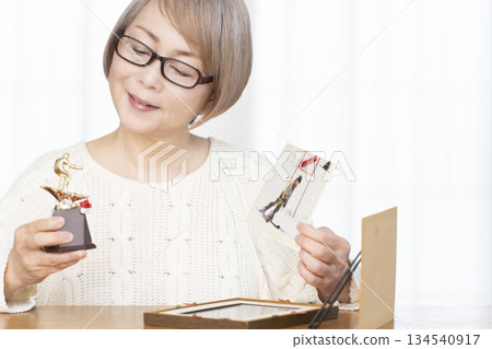 Senior woman framing photos in the living room 134540917
