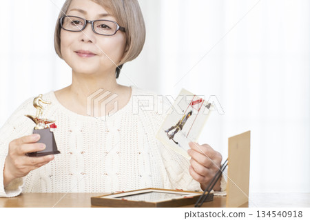 Senior woman framing photos in the living room 134540918