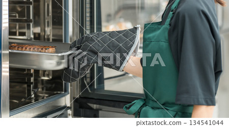 一位女烹飪人員在廚房使用蒸氣爐 134541044