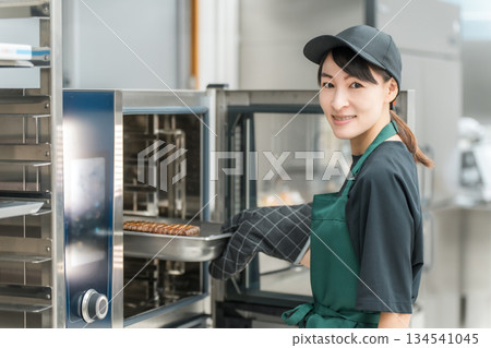 A female chef using a steam oven in the kitchen A female chef using a steam oven in the kitchen 134541045
