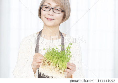 一位老婦人在廚房培育豌豆苗 134541092