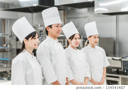 Chefs and cooks in chef coats standing in the kitchen Chefs and cooks in chef coats standing in the kitchen 134541487