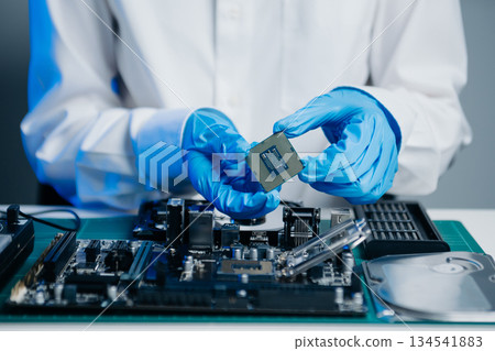 The technician is putting the CPU on the socket of the computer motherboard. electronic engineering electronic repair, 134541883