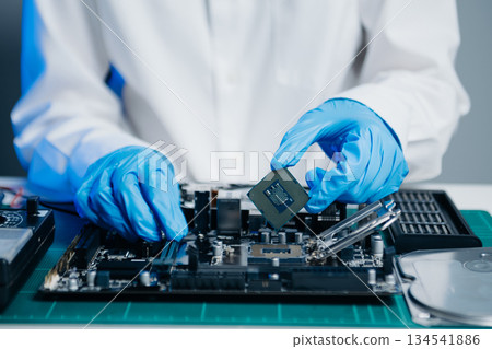 The technician is putting the CPU on the socket of the computer motherboard. electronic engineering electronic repair, 134541886