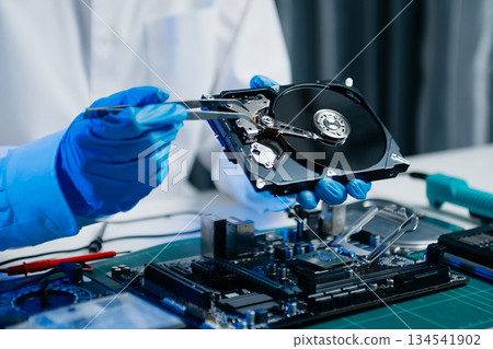 Hard disk drive on the technician's desk and a computer motherboard as a component. the concept of data, hardware, and information technology. 134541902