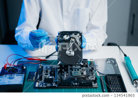 Hard disk drive on the technician's desk and a computer motherboard as a component. the concept of data, hardware, and information technology. 134541903