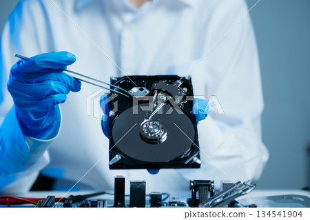 Hard disk drive on the technician's desk and a computer motherboard as a component. the concept of data, hardware, and information technology. Hard disk drive on the technician's desk and a computer motherboard as a component. the concept of data, hardware, and information technology. 134541904