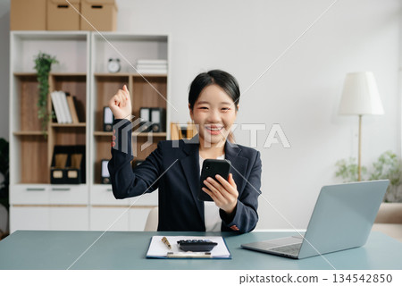 Young beautiful woman typing on tablet and laptop while sitting at the working white table Young beautiful woman typing on tablet and laptop while sitting at the working white table 134542850