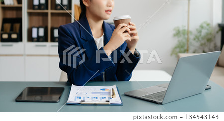 Confident Asian woman with a smile standing holding notepad and tablet at the office. Confident Asian woman with a smile standing holding notepad and tablet at the office. 134543143