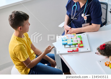 Child engages in playful activity with a medical professional using colorful shapes in a bright healthcare setting 134543511