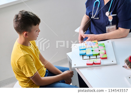 Child engages in educational activity with therapist in bright room focusing on cognitive development Child engages in educational activity with therapist in bright room focusing on cognitive development 134543557