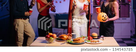 Halloween party with friends in costumes, enjoying drinks, food, and festive decorations. Perfect for autumn gatherings Halloween party with friends in costumes, enjoying drinks, food, and festive decorations. Perfect for autumn gatherings 134543785