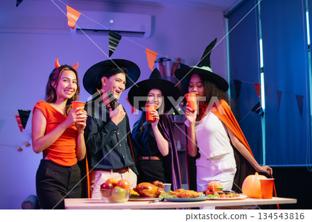 Halloween party with friends in costumes, enjoying drinks, food, and festive decorations. Perfect for autumn gatherings 134543816