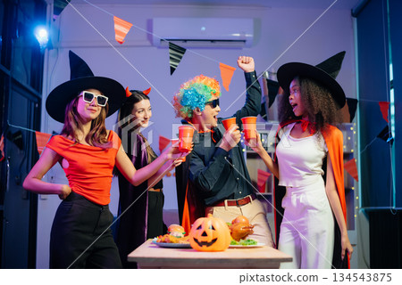 Halloween party with friends in costumes, enjoying drinks, food, and festive decorations. Perfect for autumn gatherings Halloween party with friends in costumes, enjoying drinks, food, and festive decorations. Perfect for autumn gatherings 134543875