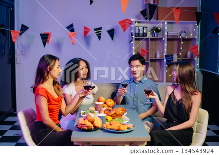Celebration with friends enjoying food, drinks, and laughter at a lively house party. Perfect for themes of joy, togetherness, 134543924