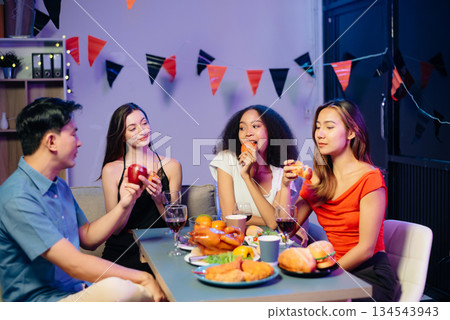 Celebration with friends enjoying food, drinks, and laughter at a lively house party. Perfect for themes of joy, togetherness, 134543943
