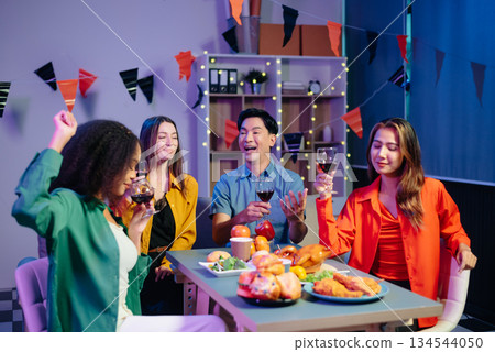 Celebration with friends enjoying food, drinks, and laughter at a lively house party. Perfect for themes of joy, togetherness, 134544050