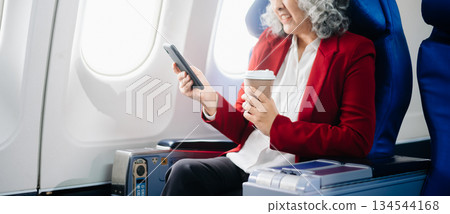 Asian seniorexecutive excels in first class, multitasking with digital tablet, laptop and smartphone. Travel in style, Asian seniorexecutive excels in first class, multitasking with digital tablet, laptop and smartphone. Travel in style, 134544168