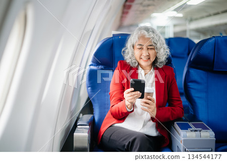 Asian seniorexecutive excels in first class, multitasking with digital tablet, laptop and smartphone. Travel in style, Asian seniorexecutive excels in first class, multitasking with digital tablet, laptop and smartphone. Travel in style, 134544177