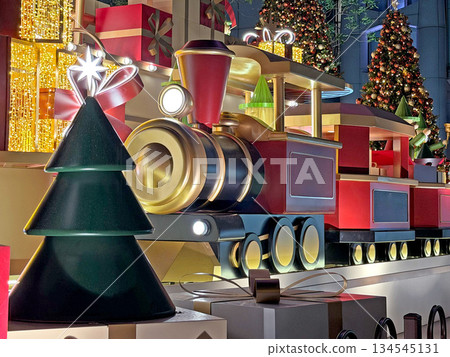 Festive holiday train decoration with Christmas trees and gift boxes illuminated by warm lights 134545131