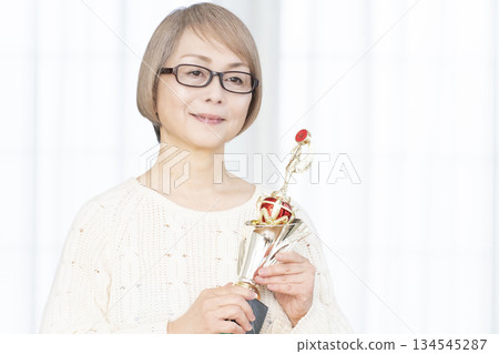 一位笑容滿面的老婦人手捧獎杯 134545287