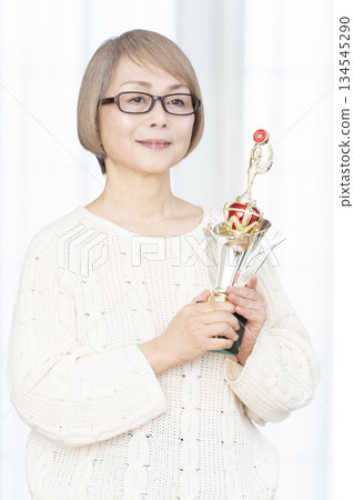 一位笑容滿面的老婦人手捧獎杯 134545290