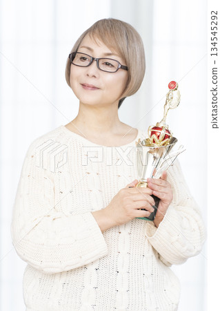一位笑容滿面的老婦人手捧獎杯 一位笑容滿面的老婦人手捧獎杯 134545292