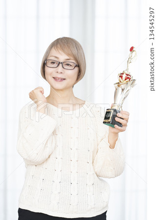 Cheerful senior woman holding a trophy 134545297