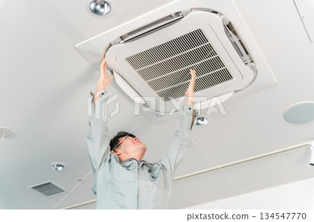A man in work clothes cleaning and inspecting air conditioners and air conditioning equipment A man in work clothes cleaning and inspecting air conditioners and air conditioning equipment 134547770