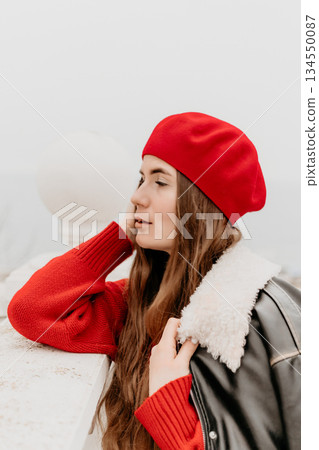 Woman beret portrait of a stylish woman in a red sweater and leather jacket, posing outdoors. Woman beret portrait of a stylish woman in a red sweater and leather jacket, posing outdoors. 134550087