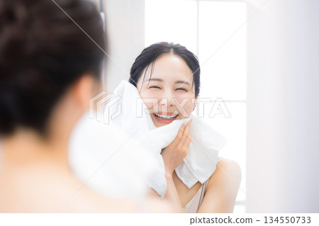 一位女士用Oru保濕保養品洗臉後對著鏡子看東西。 134550733