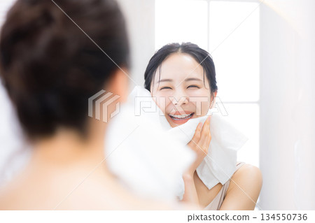 一位女士用Oru保濕保養品洗臉後對著鏡子看東西。 134550736