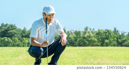 Male golfer reading the lines on the golf course green Male golfer reading the lines on the golf course green 134550924