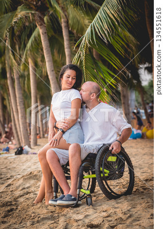 Disabled man in a wheelchair with his wife on the beach. Disabled man in a wheelchair with his wife on the beach. 134551618