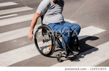 Handicapped man in wheelchair crossing street road 134551633