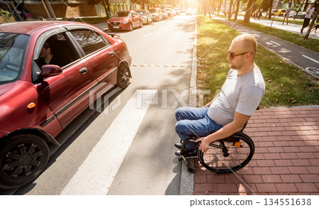 Handicapped man in wheelchair preparing to cross the road on pedestrian crossing 134551638
