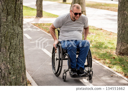 Handicapped man in wheelchair walk at the park alley 134551662