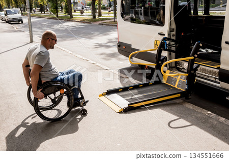 A man in a wheelchair moves to the lift of a specialized vehicle  134551666