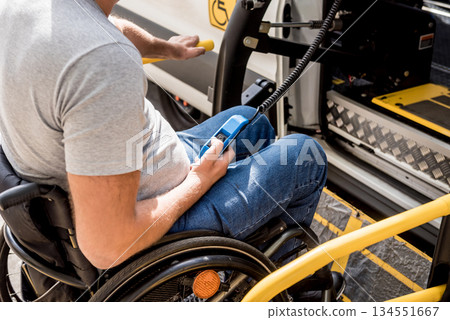 A man in a wheelchair on a lift of a vehicle for people with disabilities 134551667