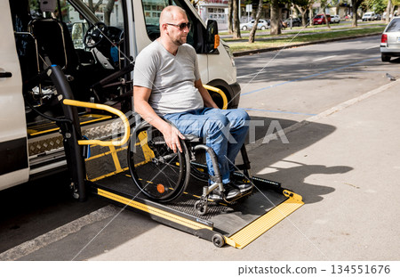 A man in a wheelchair on a lift of a vehicle for people with disabilities 134551676