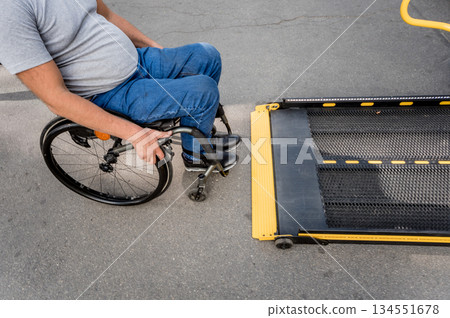 A man in a wheelchair moves to the lift of a specialized vehicle  134551678