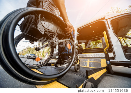 A man in a wheelchair moves to the lift of a specialized vehicle  134551686