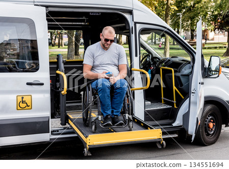 A man in a wheelchair on a lift of a vehicle for people with disabilities 134551694