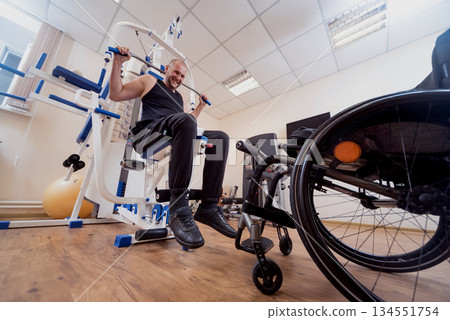 Disabled man doing strength exercises separate from the wheelchair. Disabled man doing strength exercises separate from the wheelchair. 134551754