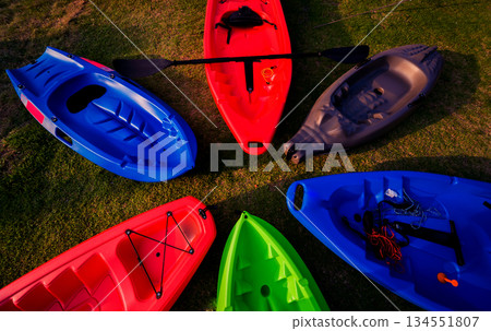Group of canoes and kayaks on a green grass 134551807