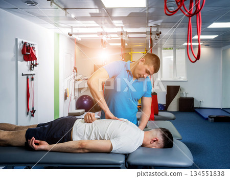 Rehabilitation therapy. Physiotherapist working with young male patient  134551838
